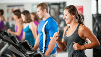 Women running on a treadmill wearing gym kit.